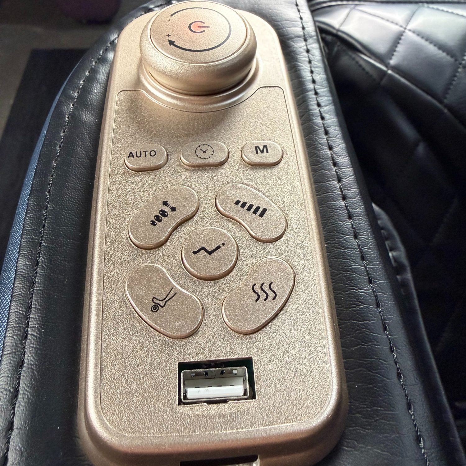 Bedieningspaneel van massagestoel met draaiknop, massageprogramma’s, intensiteitsknoppen en USB-aansluiting.