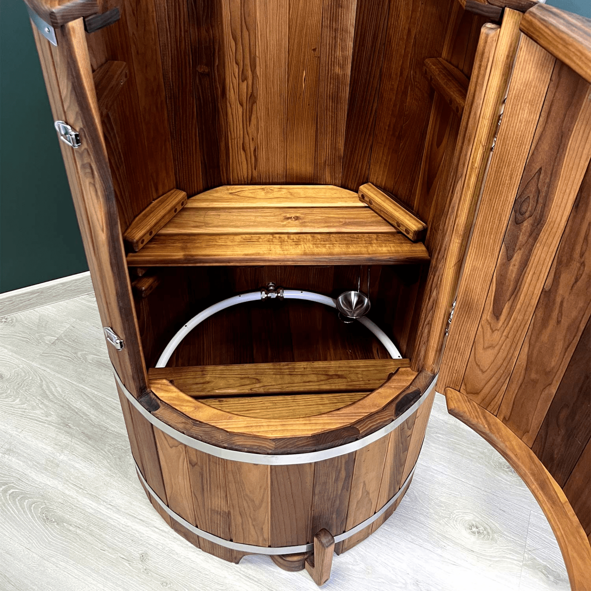 Binnenkant van een houten stoomsauna met houten zitbank, stoomslang en aromaschaaltje onderin de sauna