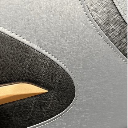 close-up van grijze massagestoelbekleding met textuur, donker inzetstuk en goudaccent