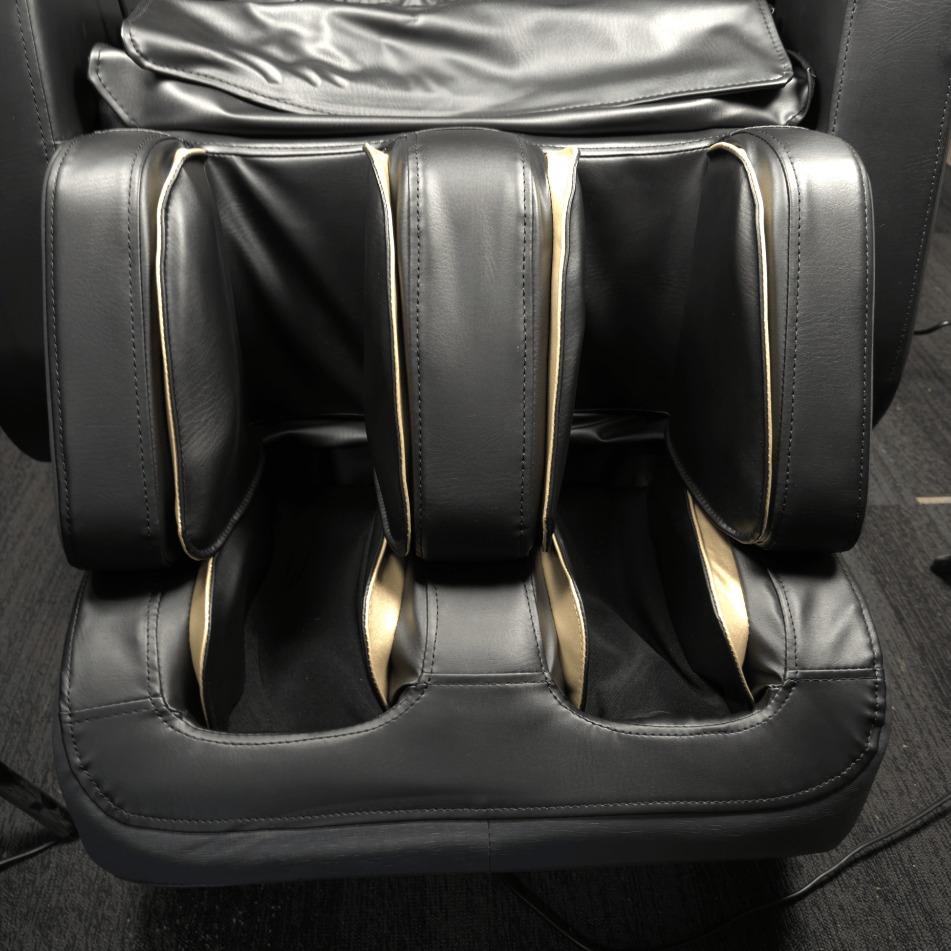 close-up van zwart voet en kuitgedeelte van massagestoel met goudkleurige accenten