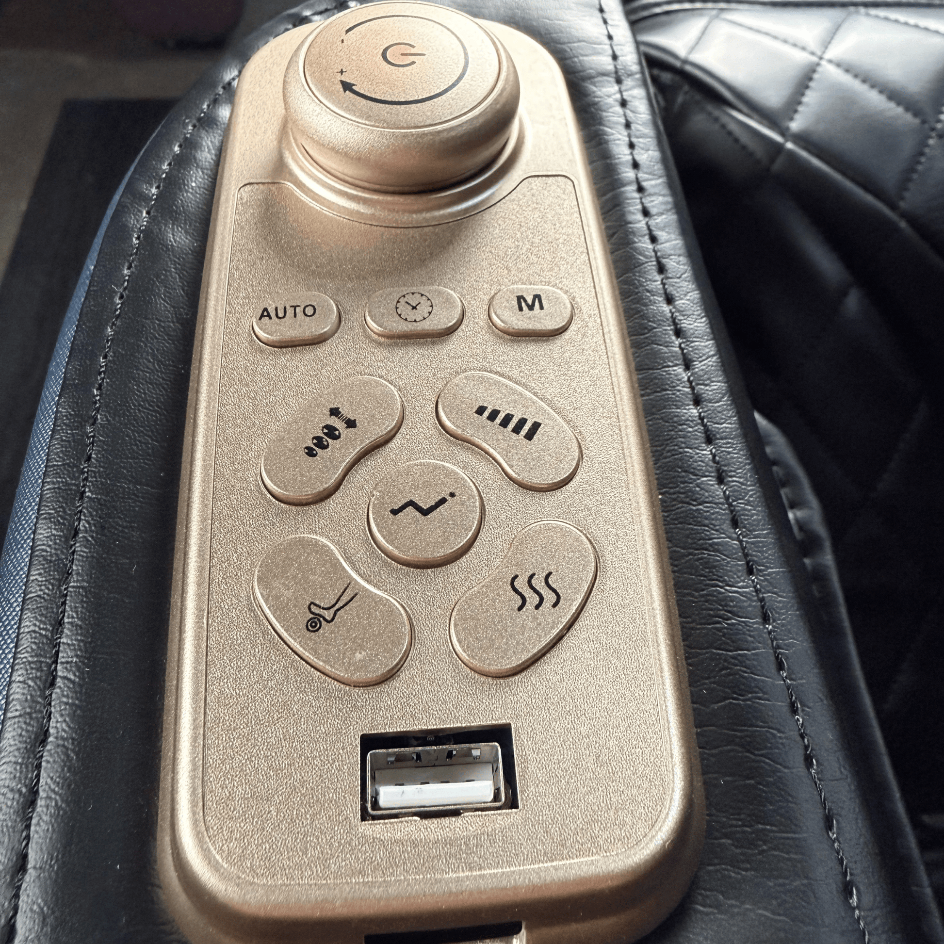 close-up van goudkleurig bedieningspaneel op armleuning van zwarte massagestoel met usb poort