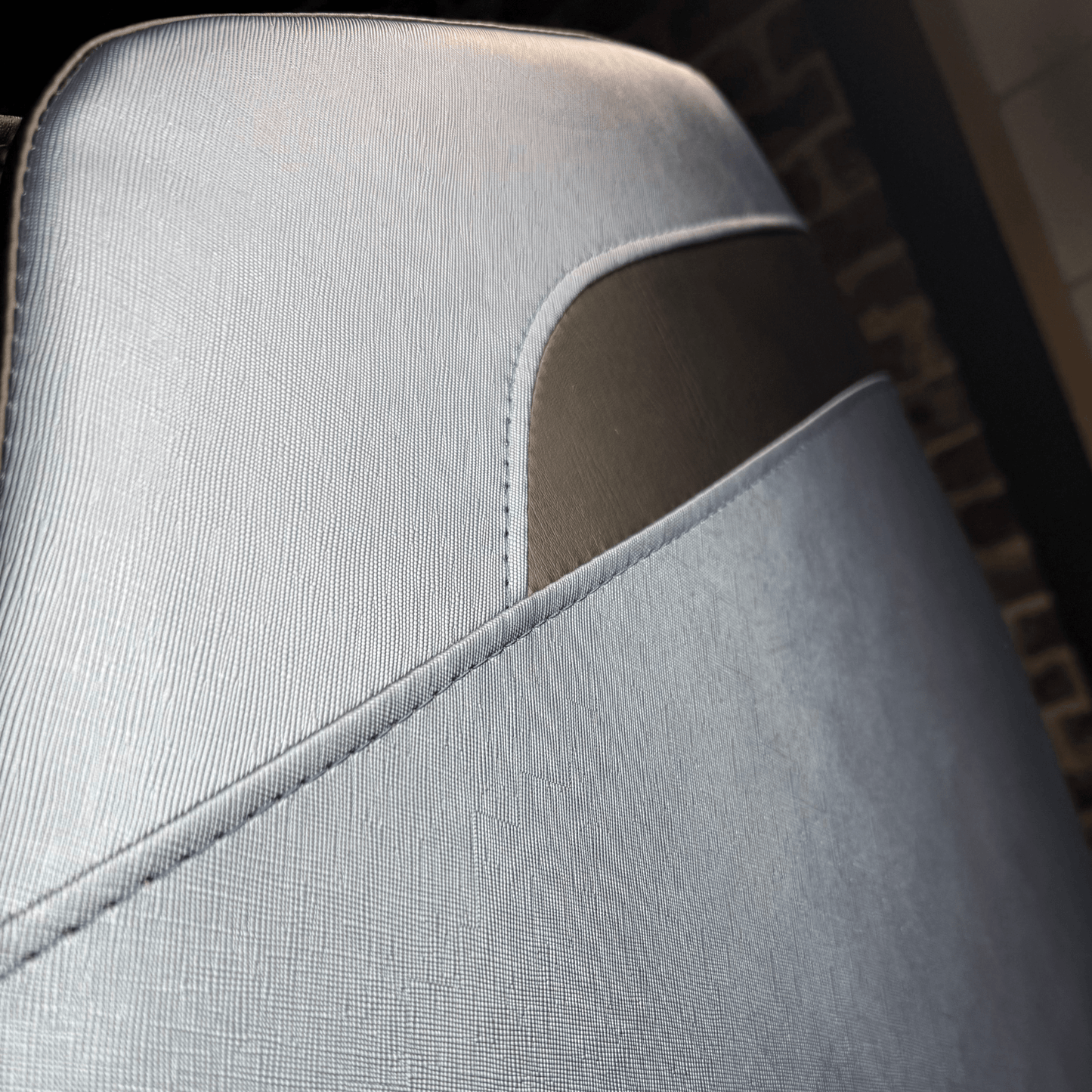 close-up van lichtblauw zijpaneel van massagestoel met donker detail