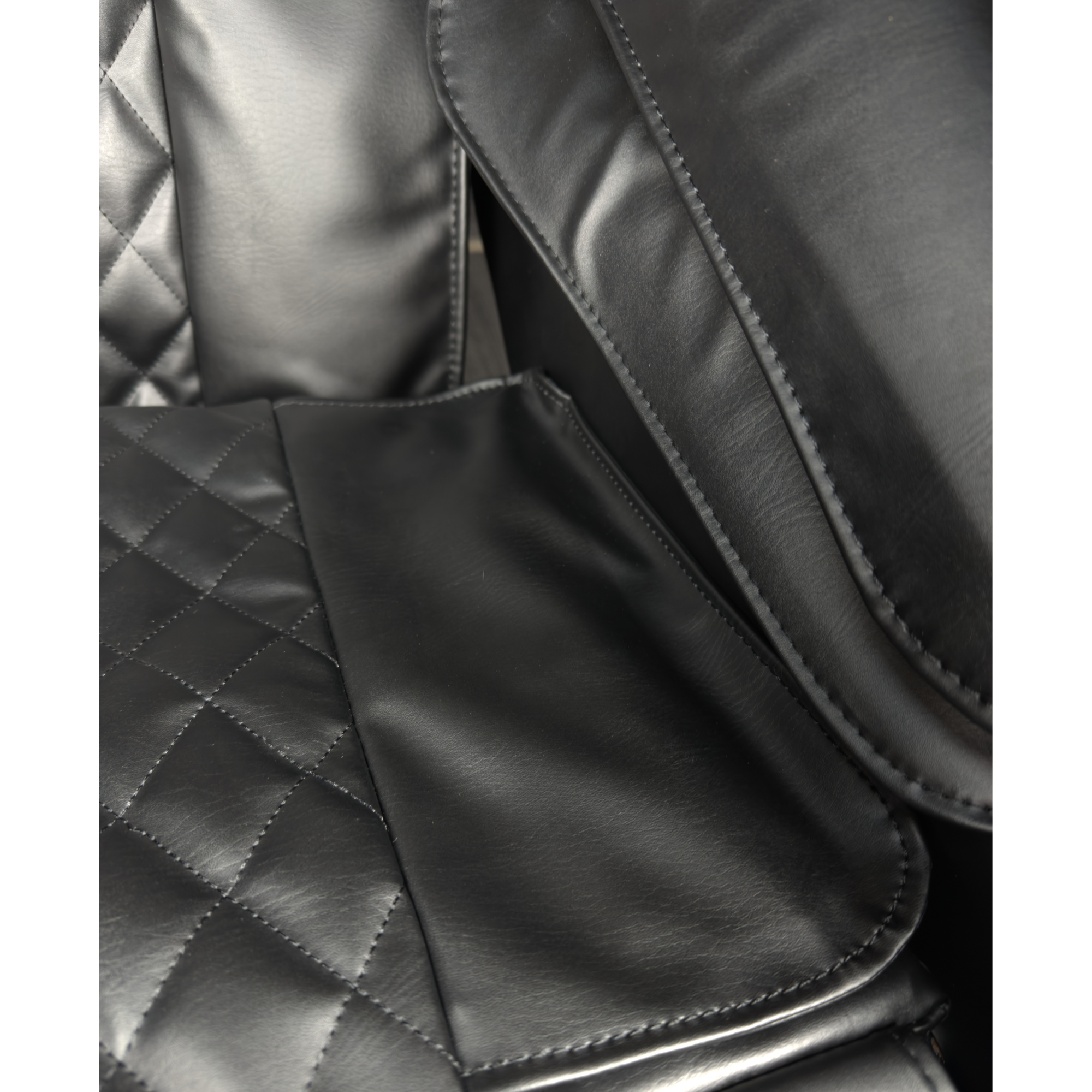 Detail van zwart zitvlak van massagestoel met gewatteerd kunstleer en stiknaden